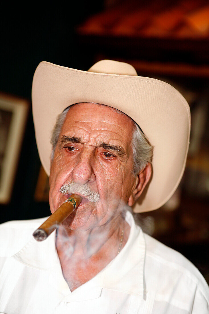 Mature man smoking a cigar, Calle Ocho, Miami, Florida, USA