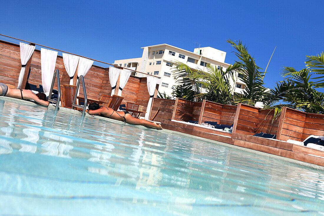 Two women sunbathing at the rooftop pool of the Catalina Beach Club Hotel, South Beach, Miami Beach, Florida, USA