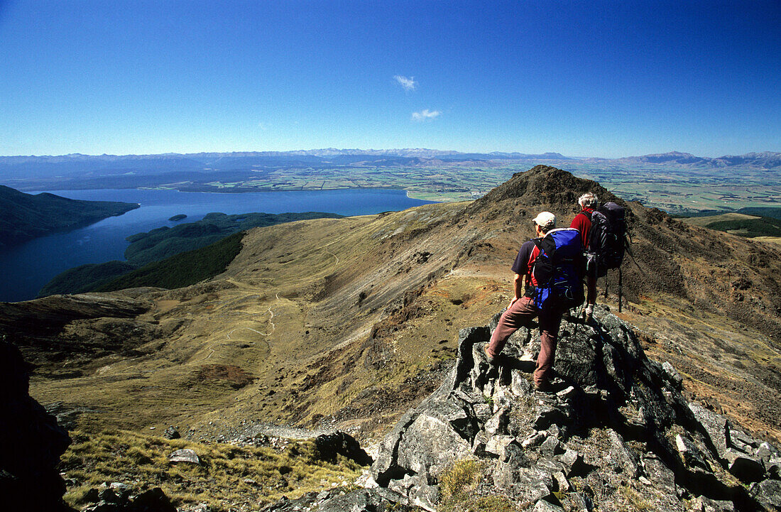 Zwei Trekker besteigen den Mt. Luxmoore in den Kepler Mountains, Blick auf den See Te Anau, Fiordland Nationalpark, Südinsel, Neuseeland, Ozeanien