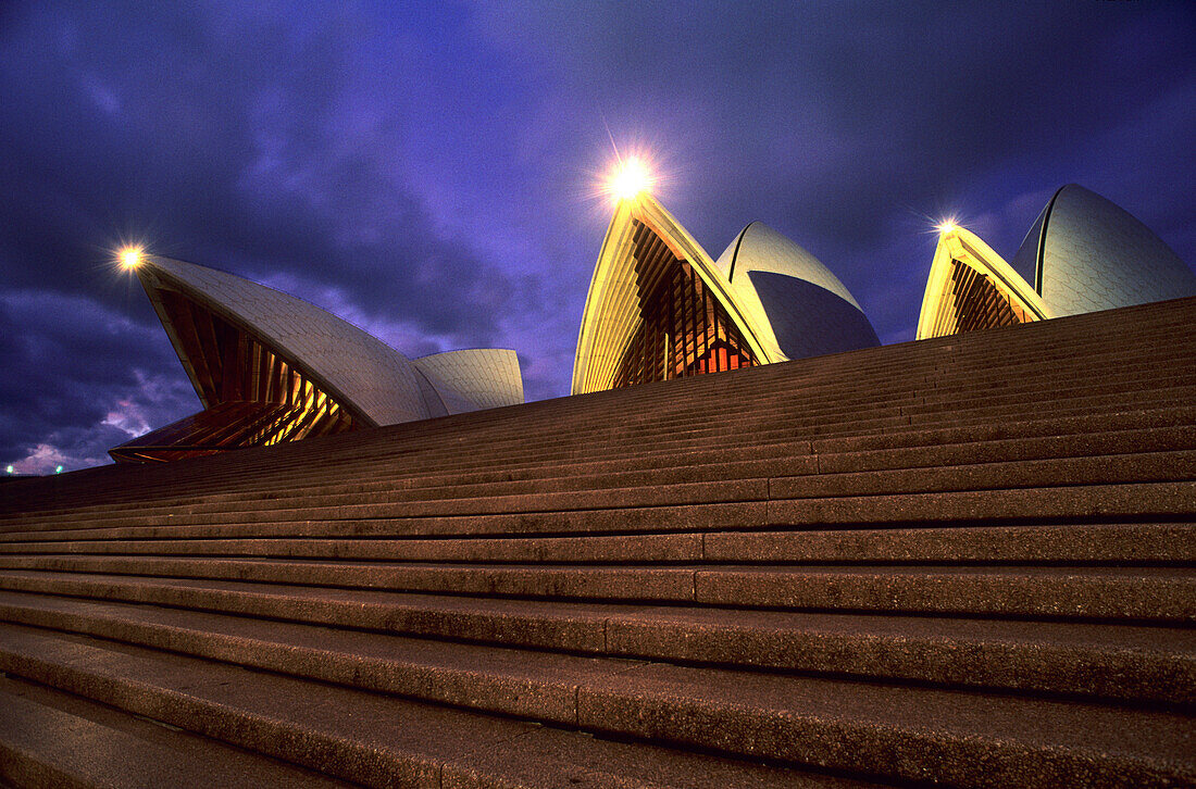 Blick auf Stufen vor dem beleuchteten Opernhaus am Abend, Sydney, New South Wales, Australien