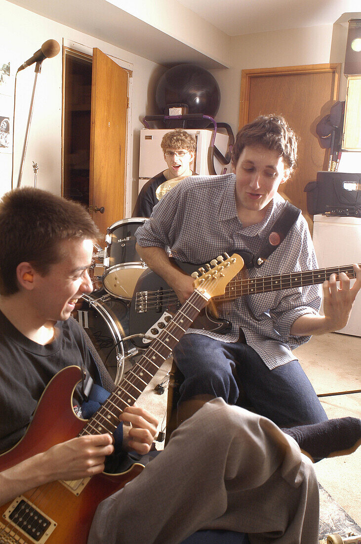 Teen age boys with dreams of being rock stars, practice playing guitars and drums in the basement of their home. Vancouver, BC, Canada