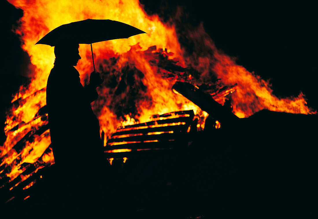 Man with umbrella in front of fire