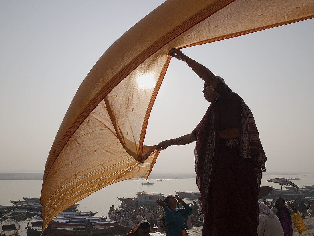 A woman dries a wet sari in the early morning sun after bathing in the Ganga river (in accordance with the Hindu belief that such bathing will wash away her sins) in Varanasi, India, a sacred Hindu pilgrimage site.