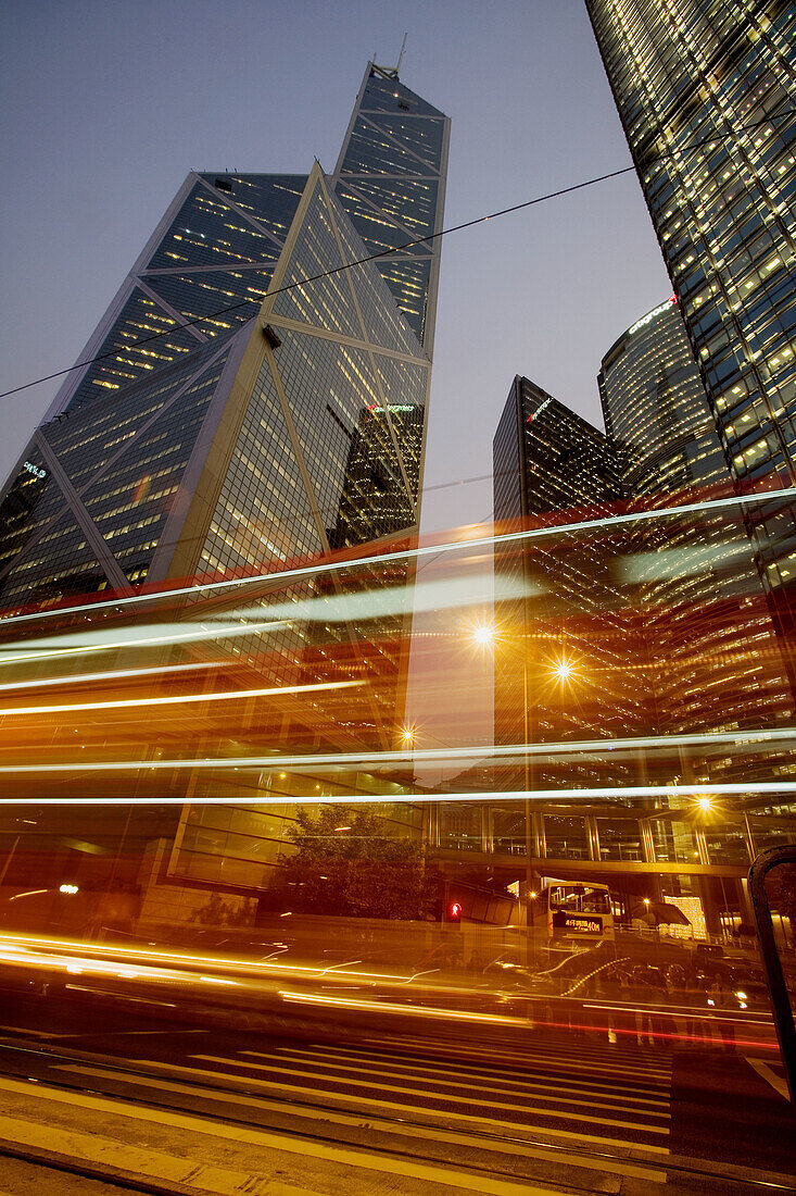 Streaked lights of a bus pass in front of skyscrapers rising into the night sky in this long exposure photograph. The Bank of China building - designed by I. M. Pei - is at left. Hong Kong, China, Asia.