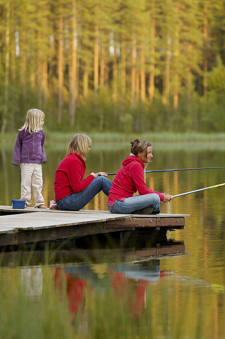 Three persons on a jetty, two are fishing, Vasterbotten, Sweden (July 2005)