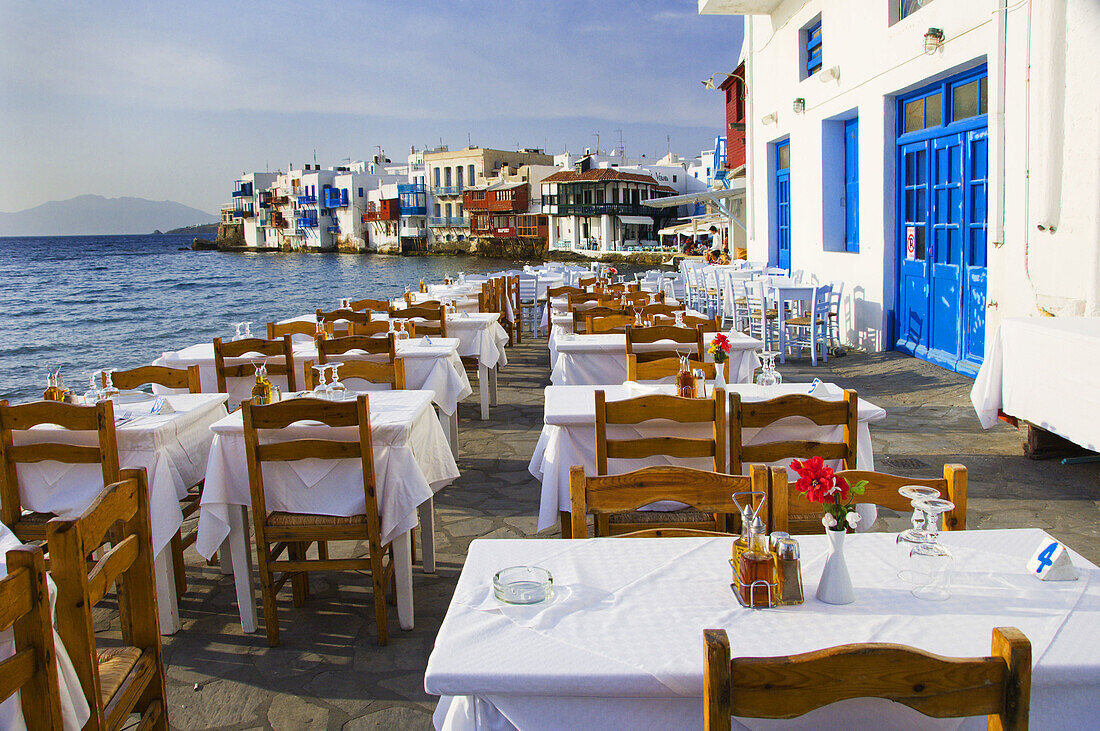 Restaurants with table and chairs in the Little Venice area overlooking the Aegean Sea in Hora on the Greek Island of Mykonos, Greece.