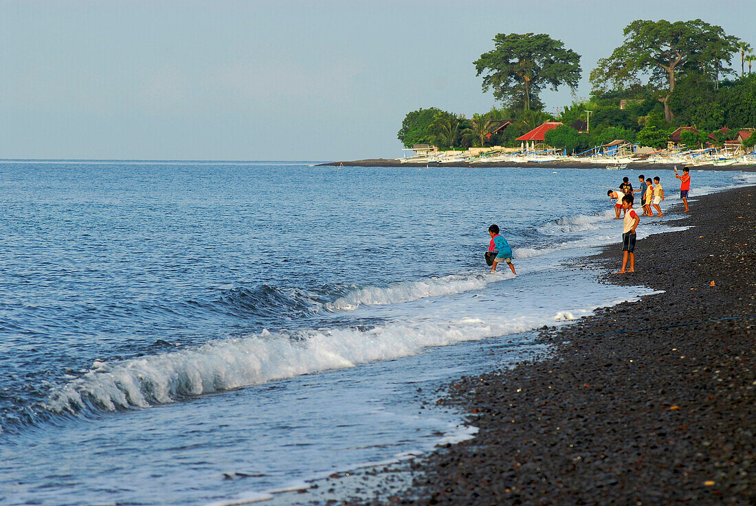 People standing on the waterfront in the evening sun, Eastern Bali, Indonesia, Asia