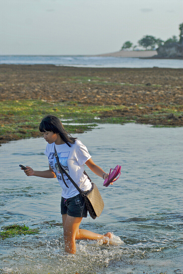 Balinesin watet bei Ebbe durchs Wasser, Pura Geger, Süd Bali, Indonesien, Asien