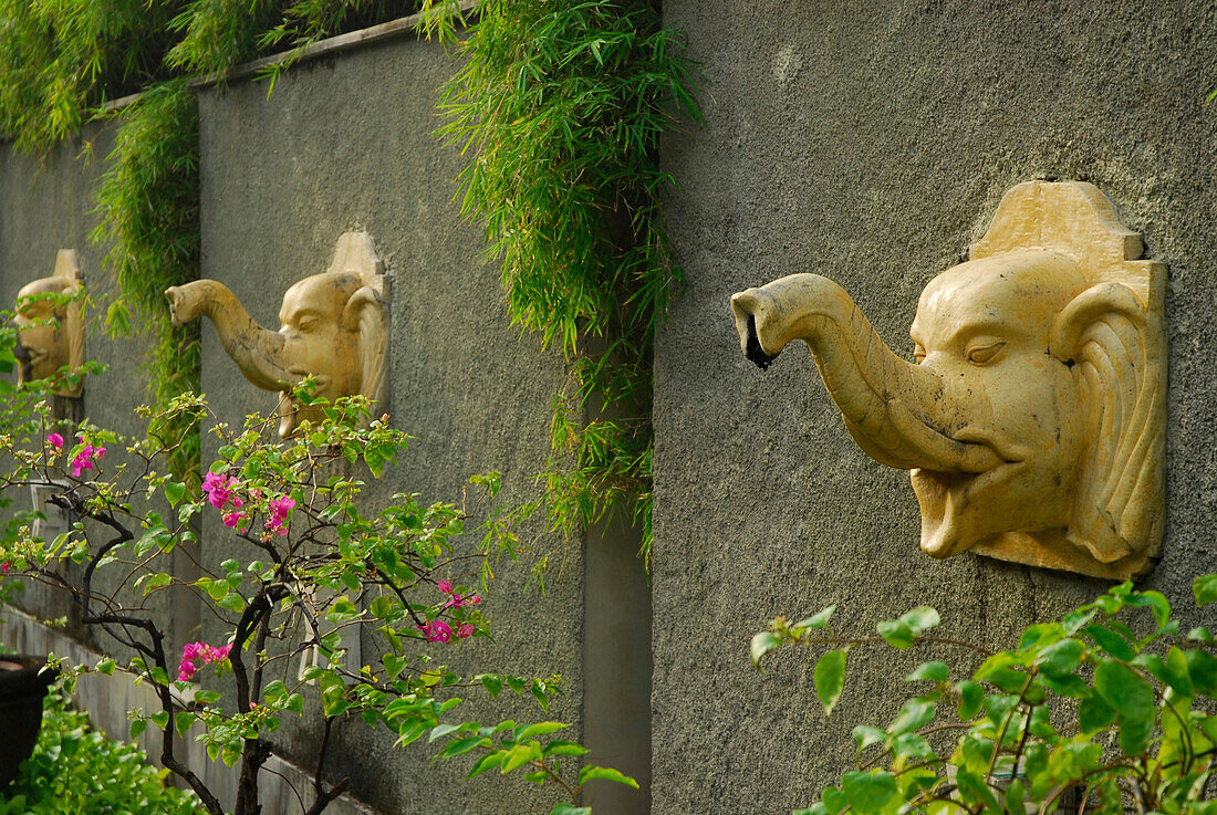 Mauer mit Skulpturen im Garten des Alam Kulkul Hotel, Kuta, Bali, Indonesien, Asien