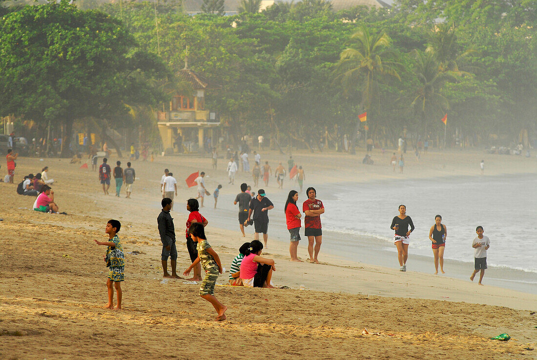 Einheimische am morgendlichen Strand von Kuta, Bali, Indonesien, Asien