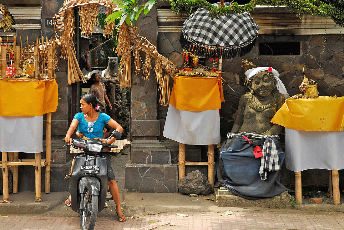 A woman on a motor scooter in front of the entrance of a house, Mas, Bali, Indonesia, Asia