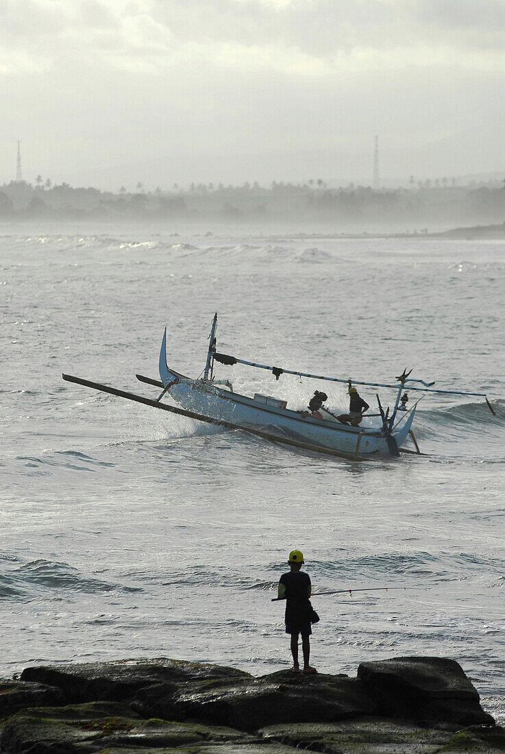 Fischerboot auf den Wellen und Angler auf einem Felsen, Pekutatan, Bali, Indonesien, Asien