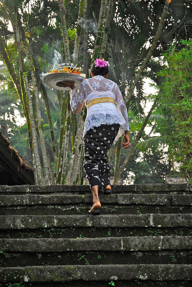 Mature woman with oblation on stairs,  Amandari Hotel, Yeh Agung, Bali, Indonesia, Asia