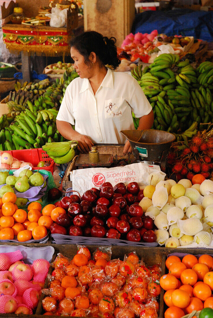 Eine Frau steht an einem Marktstand mit Obst, Ubud, Zentral Bali, Indonesien, Asien