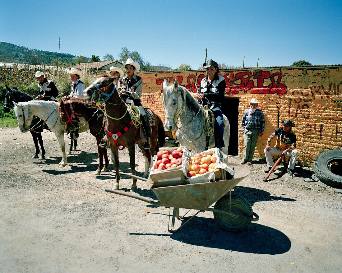 Eine Schubkarre mit Äpfeln und Männer auf Pferden vor einer Werkstatt, Texocuixpan, Provinz Tlaxcala, Mexico, Amerika