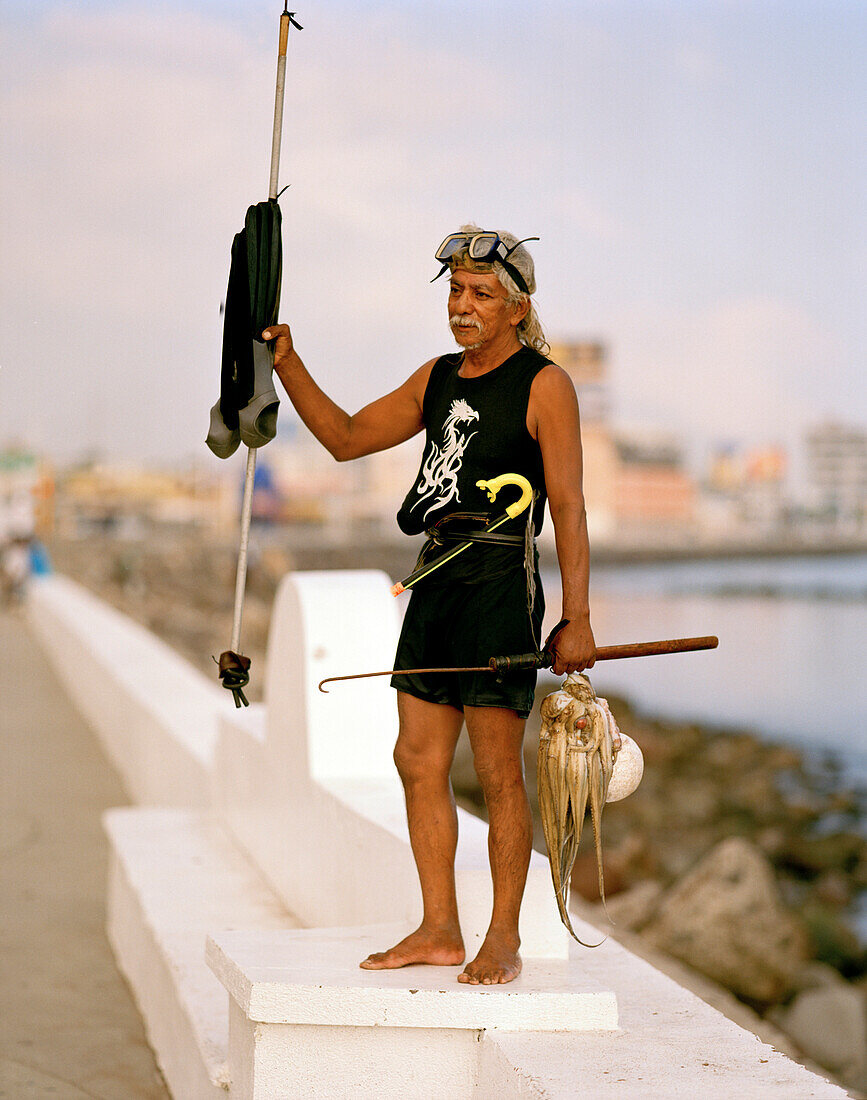 Ein Taucher mit Harpune und Tintenfischen steht an einer Promenade, Veracruz, Provinz Veracruz, Mexico, Amerika