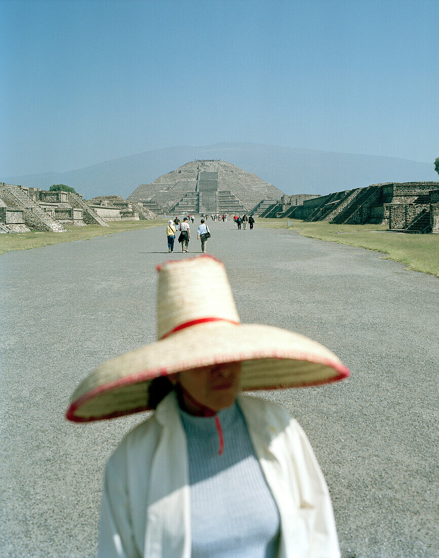 Woman wearing a sombrero standing on the road in front of the moon palace, temple complex Teotihuacan, Mexico, America