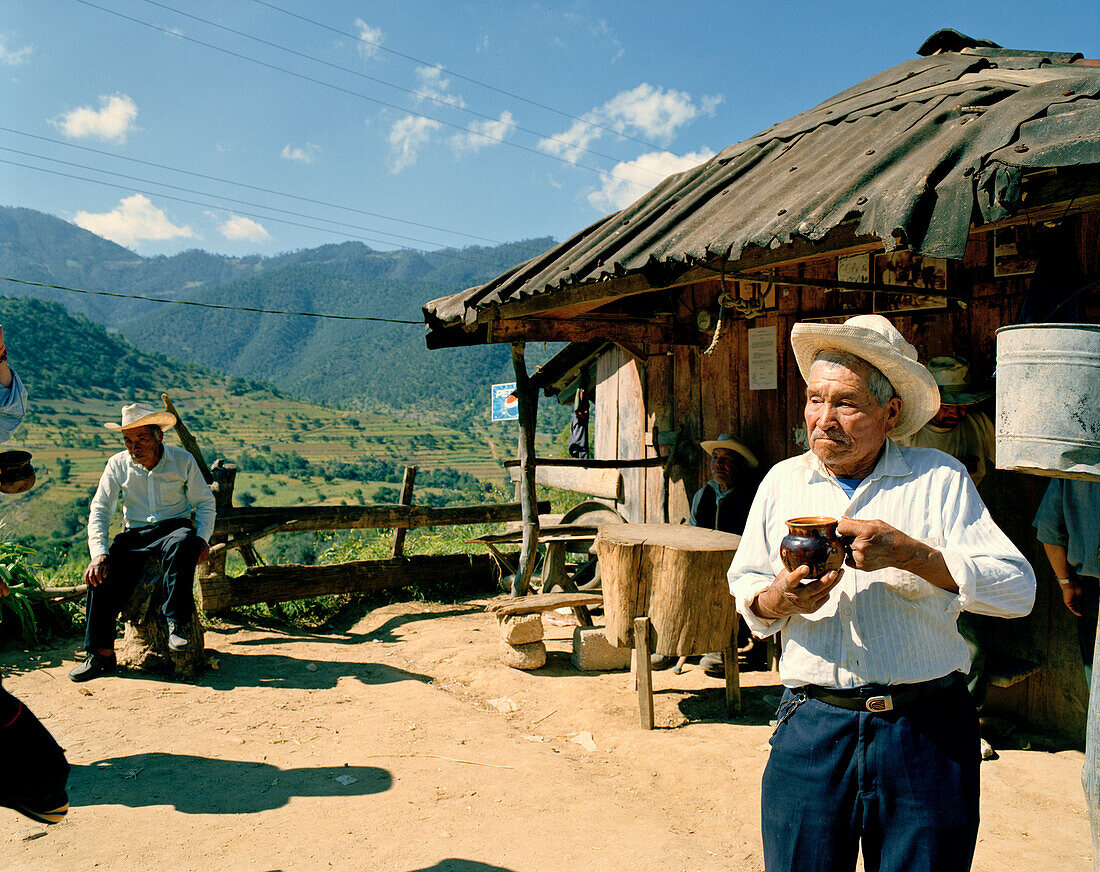 Three men in front of a hut in the sunlight, Puebla province, Mexico, America
