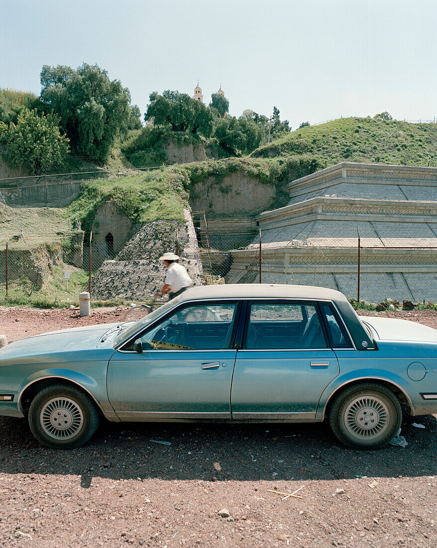 Parking car in front of overgrown Aztec pyramid, Cholula, Puebla province, Mexico, America