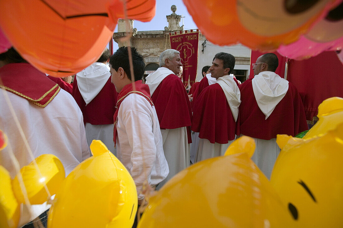 Monks in traditional costumes preparing for the Easter processions viewed through balloons. Ispica. Sicily. Italy