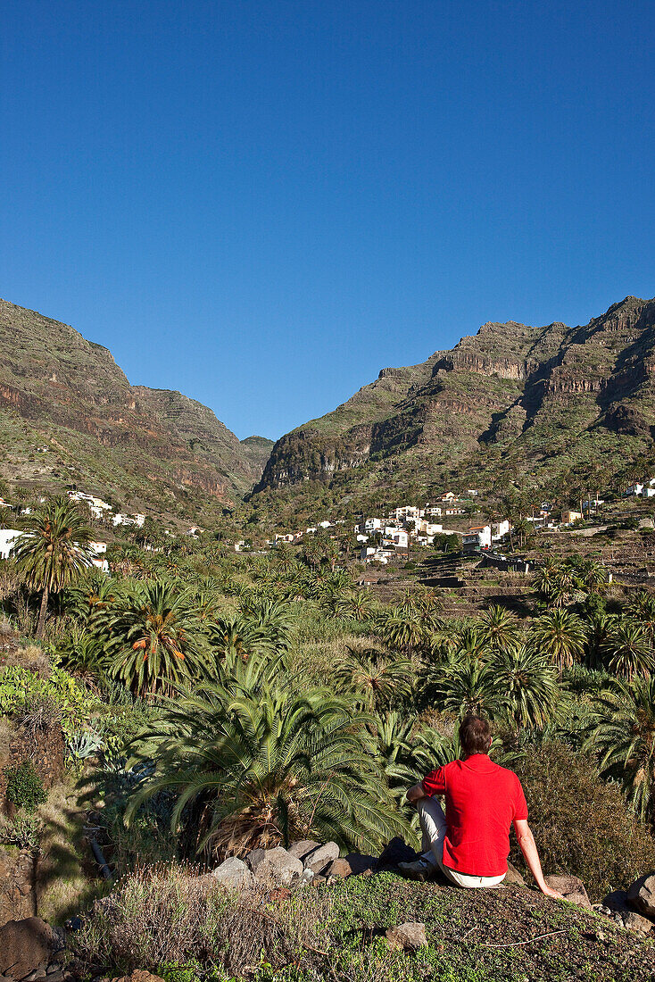 Hiker under blue sky looking at the view, Valle Gran Rey, La Gomera, Canary Islands, Spain, Europe