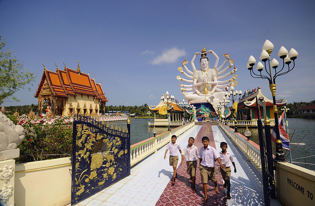 Four boys visiting Nuam Na Ram Temple, North coast, Ko Samui, Thailand