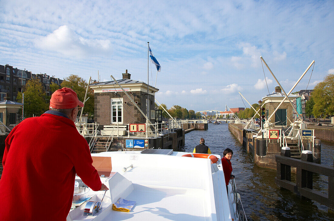 Menschen fahren mit dem Hausboot auf dem Fluss Amstel, Amsterdam, Holland, Europa