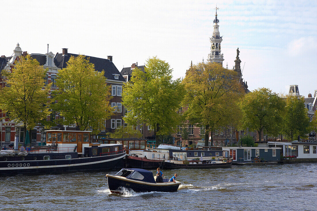 Ein Motorboot fährt auf dem Fluss Amstel an Frachtern vorbei, Amsterdam, Holland, Europa