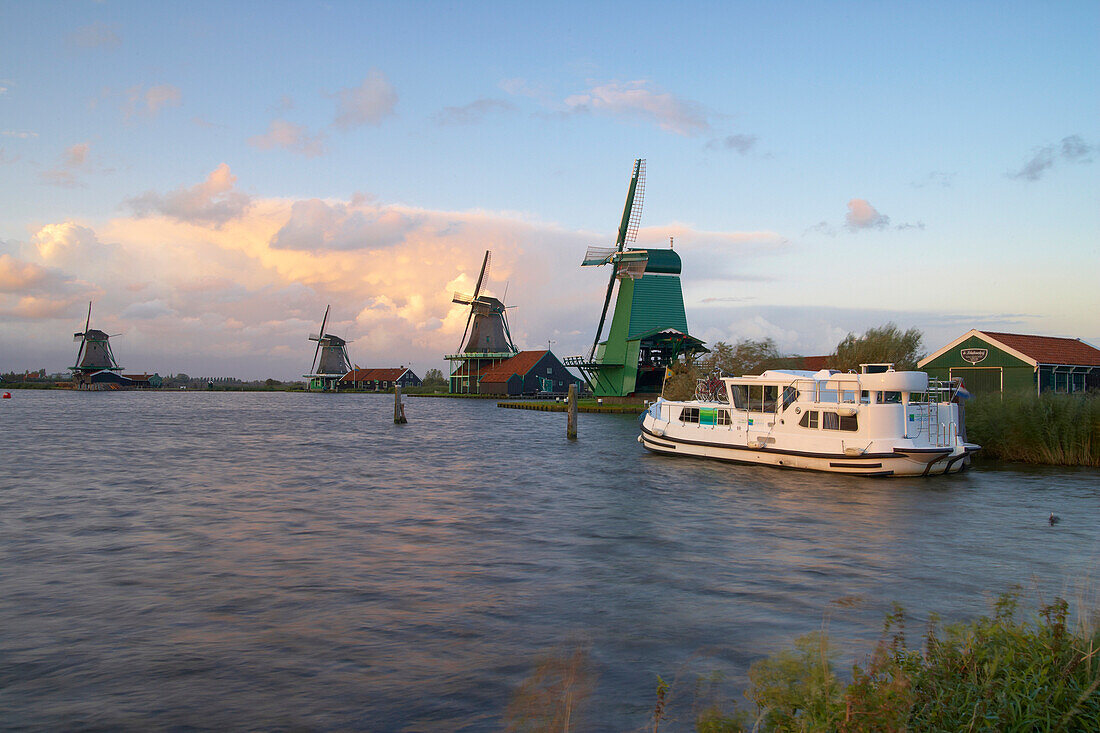 A boat and windmills in the evening, Open-air museum Zaanseschans at the river Zaan, Netherlands, Europe
