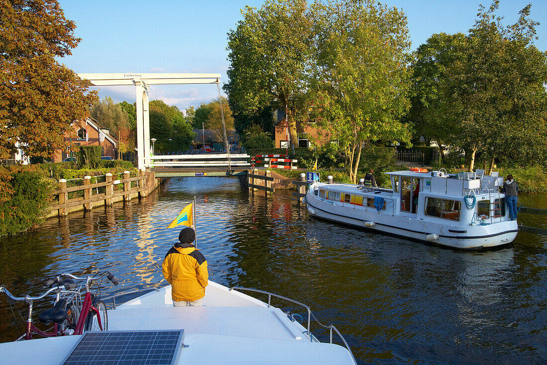 Two houseboats on the river Vecht approaching a bascule bridge, Netherlands, Europe