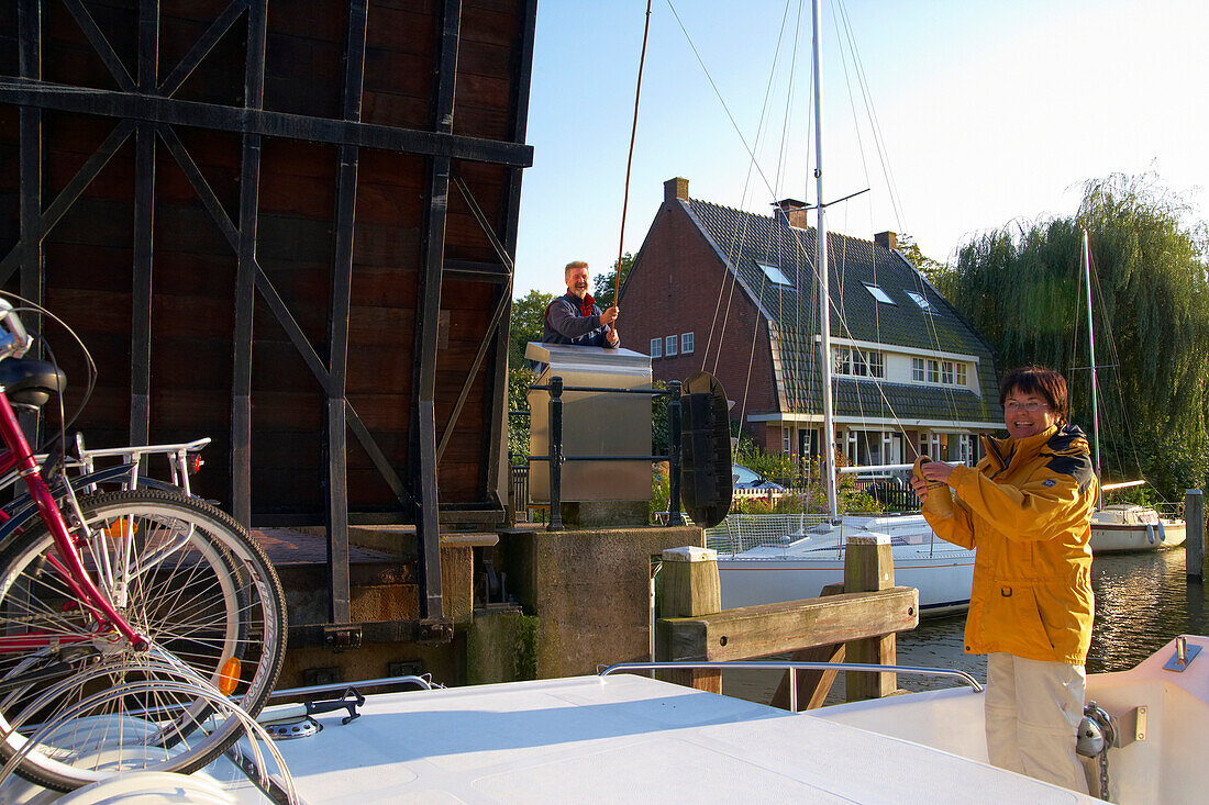 Frau auf einem Hausboot auf dem Fluss Vecht zahlt Brückenzoll, Vreeland, Holland, Europa
