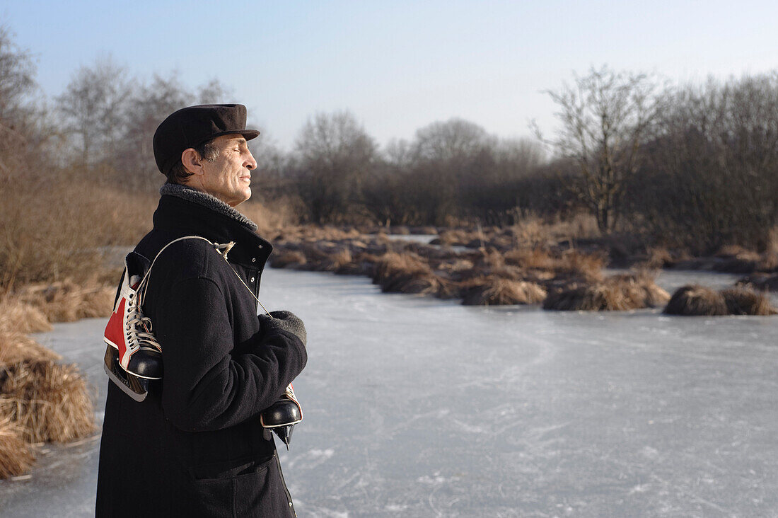 Senior man with ice skates at lake Ammersee, Upper Bavaria, Germany