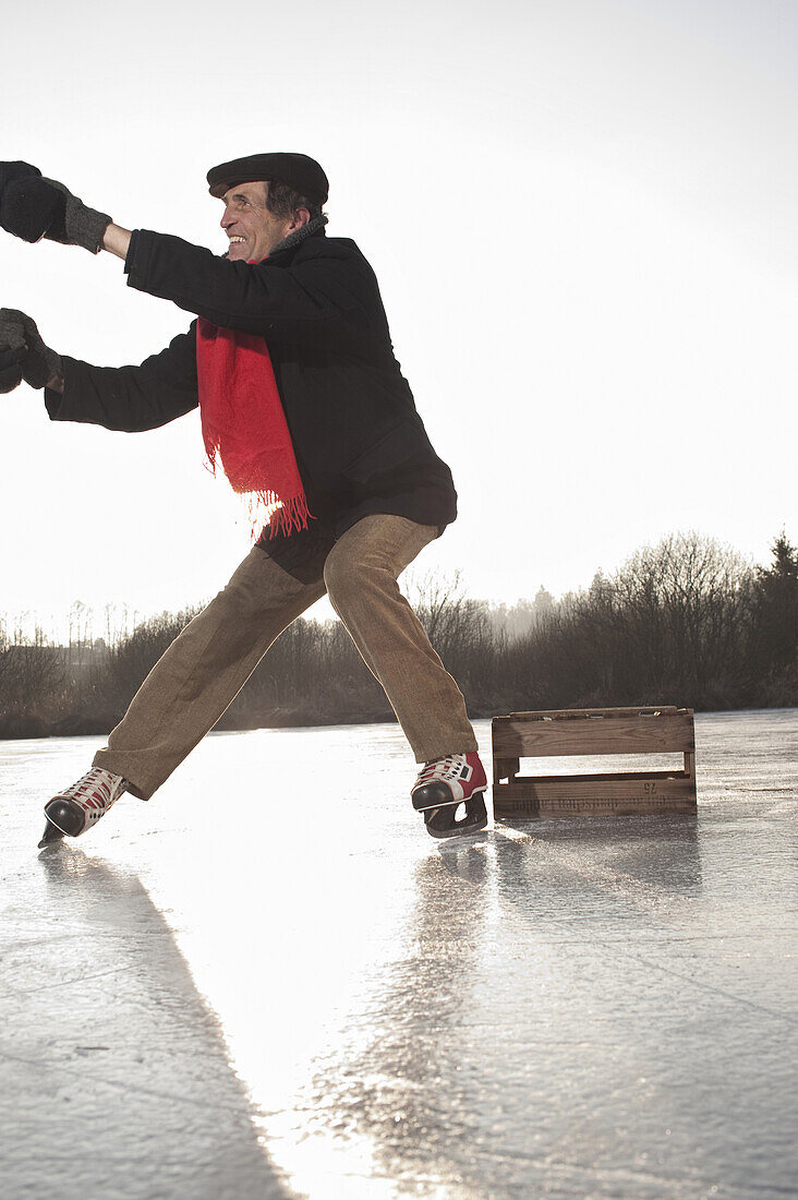 Person helping ice skater to stand up, Lake Ammersee, Upper Bavaria, Germany