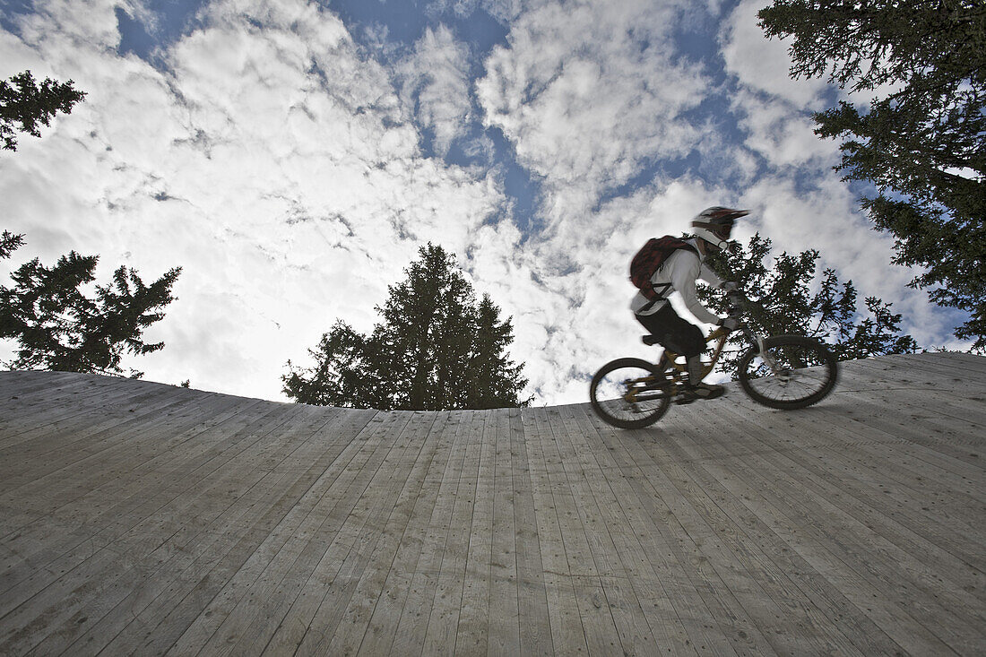 Mountainbiker fährt an einer Holzwand entlang, Lillehammer, Norwegen
