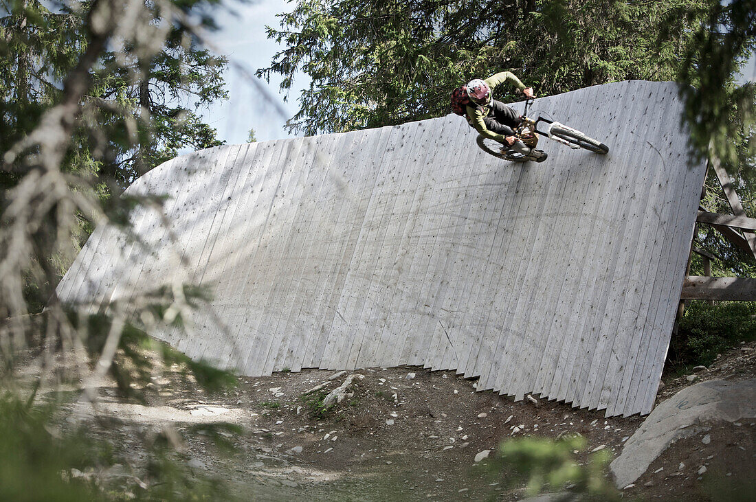 Mountainbiker riding on a vertical timber wall, Lillehammer, Norway