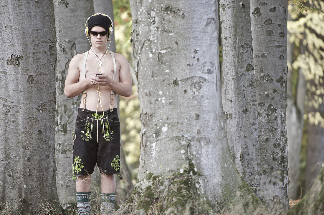 Junger Mann in Lederhosen steht im Wald, Kaufbeuren, Bayern, Deutschland