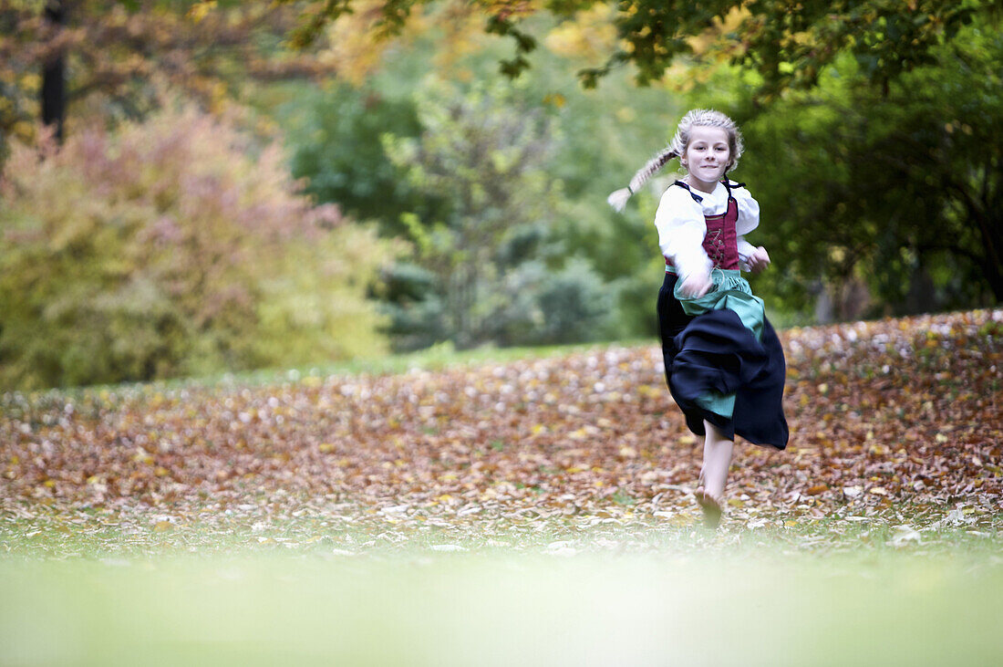 Mädchen im Dirndl rennt durch einen Park, Kaufbeuren, Bayern, Deutschland