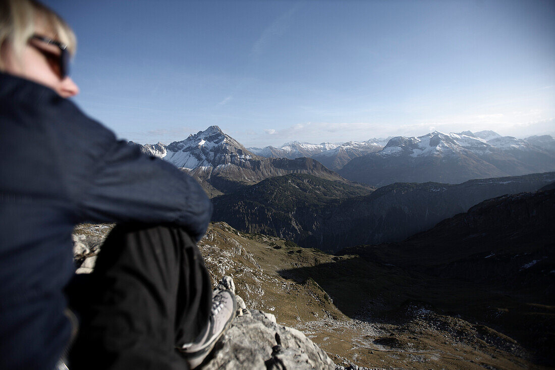 Woman sitting on a rock in the mountains in front of an alp panorama, Oberstdorf, Bavaria, Germany