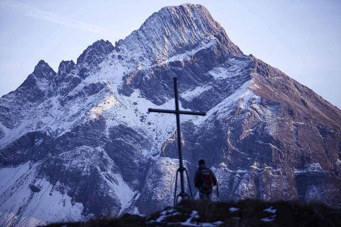 Mann steht am Gipfelkreuz mit Blick auf die Alpen, Oberstdorf, Bayern, Deutschland