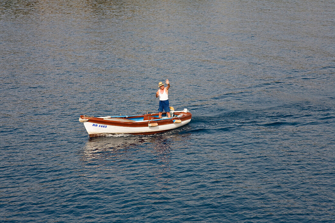 Waving fisherman in his boat, Mediterranean sea, Europe