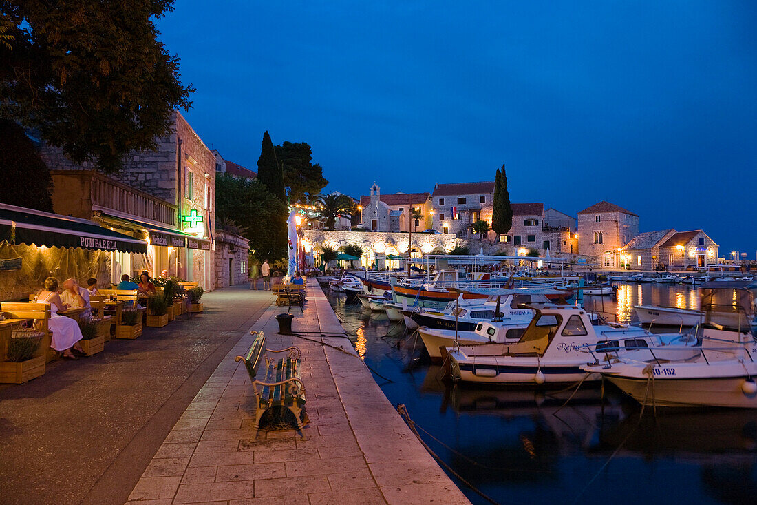 Menschen sitzen abends vor einer Taverne am Hafen Bol, Insel Brac, Dalmatien, Kroatien, Europa