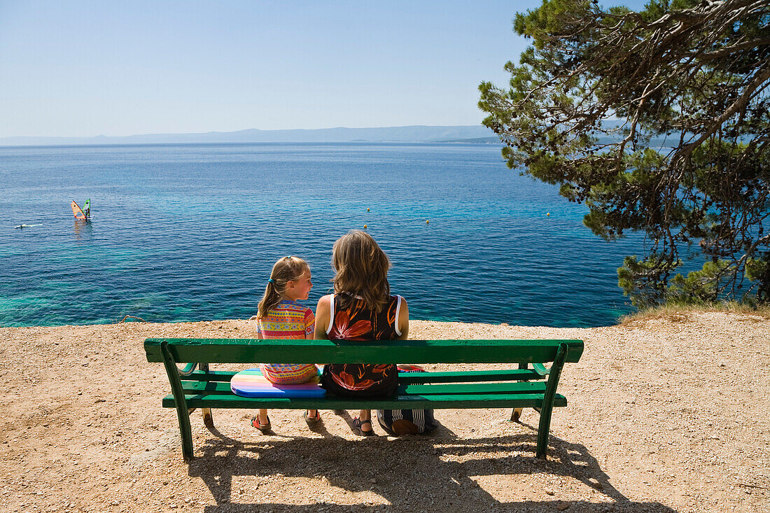 Mutter und Kind sitzen auf einer Bank am Meer, Bol, Insel Brac, Dalmatien, Kroatien, Europa