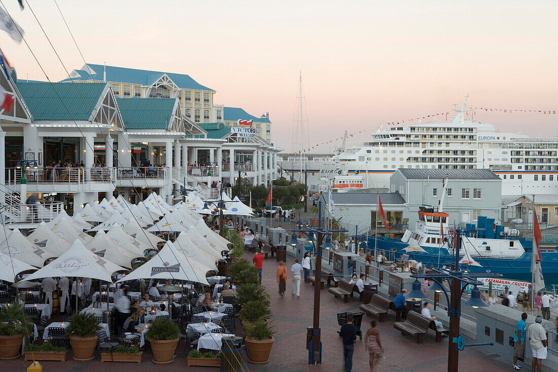 Restaurants an der Waterfront mit Kreuzfahrtschiff MS Europa an der Pier im Dämmerlicht, Kapstadt, Western Cape, Südafrika, Afrika