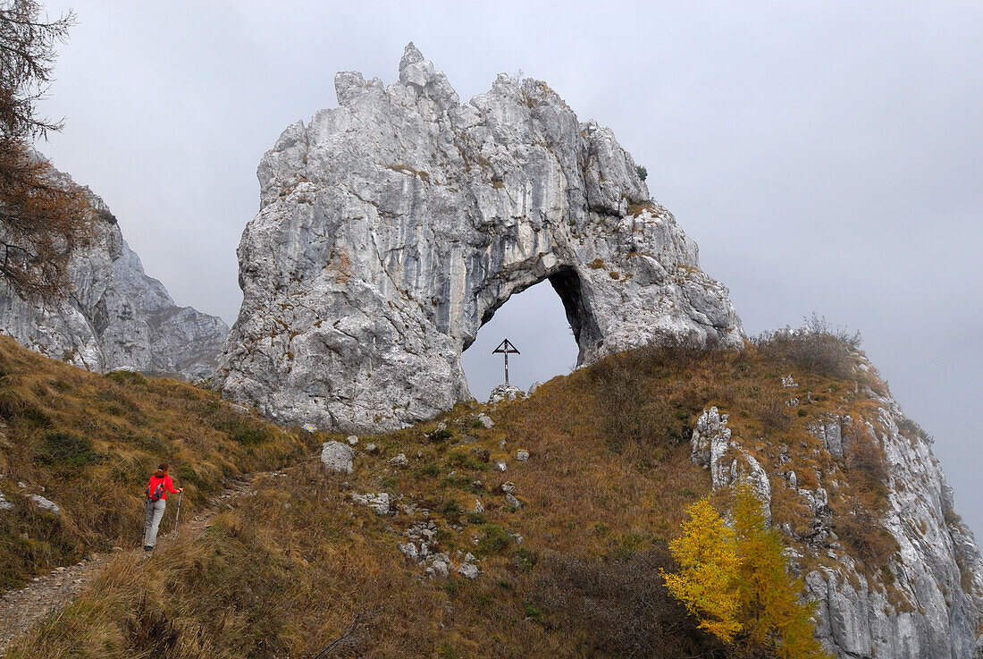 Frau wandert zu einem Felsenbogen, Grigna Settentrionale, Bergamasker Alpen, Como, Lombardei, Italien