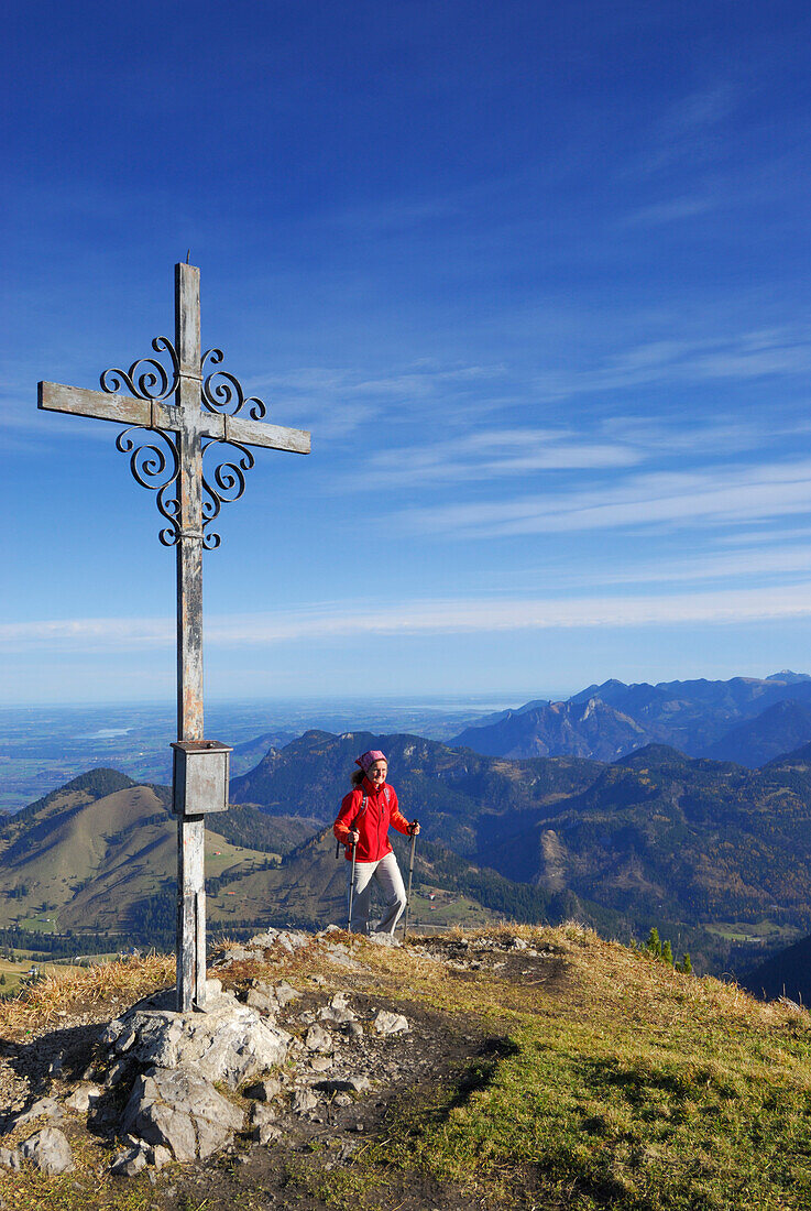 Woman reaching summit cross, Kleiner Traithen, Bavarian foothills, Bavaria, Germany
