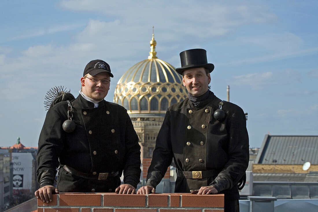 Chimney sweeps standing on roof, dome of New Synagogue, in background, Berlin, Germany
