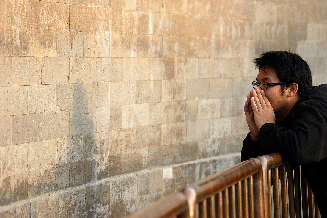 A visitor in front of Echo Wall talk to his friends in the other end of the wall in Temple of heaven. Beijing. China