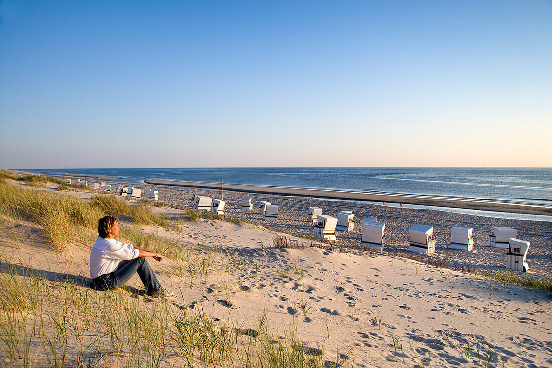 Frau sitzt in einer Düne, Rantum, Sylt, Nordfriesland, Schleswig-Holstein, Deutschland