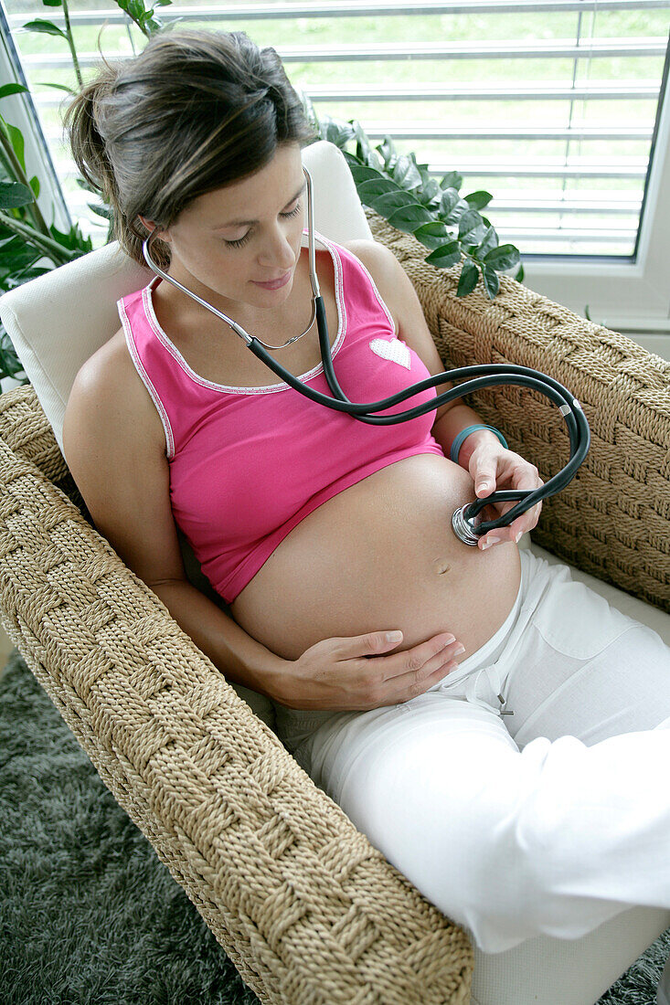 Schwangere Frau hält Stethoskop auf den Bauch