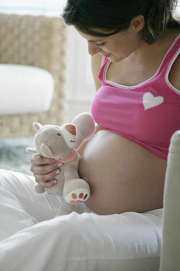 Pregnant woman with stuffed toy on belly, Styria, Austria